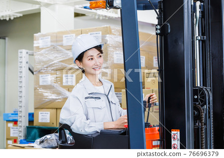 一個戴著頭盔、操作叉車的女人 76696379