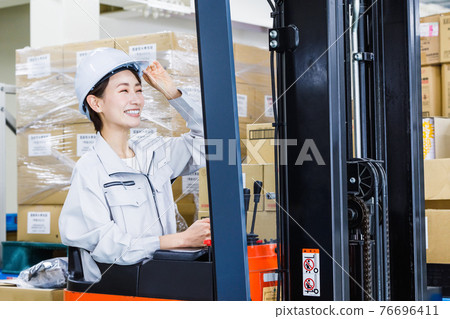 一個戴著頭盔、操作叉車的女人 76696411