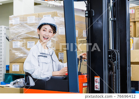 一個戴著頭盔、操作叉車的女人 76696412