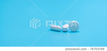 Round white tablets pills and oval tablets pills on blue background. Pharmacy shop banner. Prescription drugs. Pharmaceutical industry. Painkiller, antibiotics, and antacid tablet pills. Pharmaceutic. 76703598