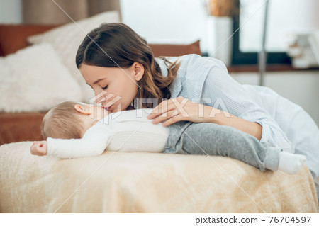 Caring mother bending over sleeping child Caring mother bending over sleeping child 76704597