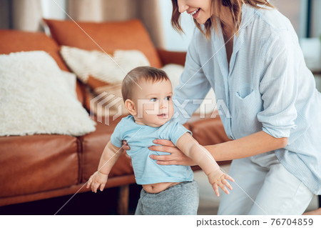 Cheerful active child and mother supporting him 76704859