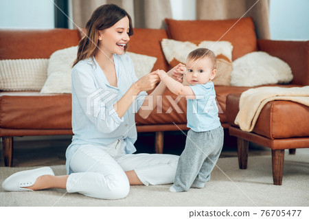 Woman holding hands of child holding balance 76705477