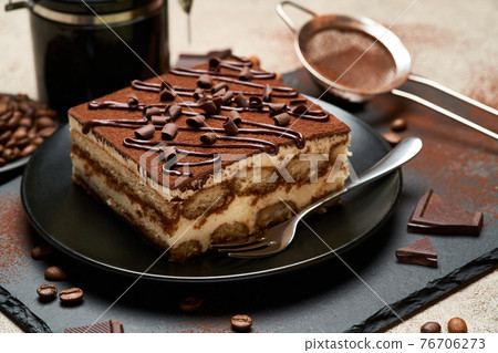 Portion of Traditional Italian Tiramisu dessert and hand coffee grinder on grey concrete background 76706273