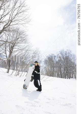 A young woman standing with a snowboard looking at the camera Snowboard image 76706765