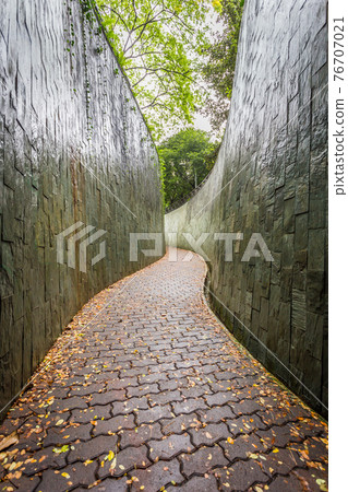 Modern architecture of a narrow, high walled corridor in a park at Singapore. Modern architecture of a narrow, high walled corridor in a park at Singapore. 76707021