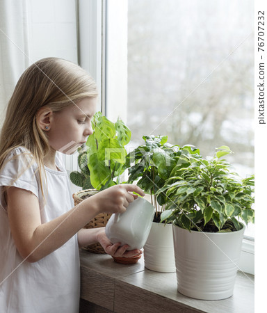 Little girl watering houseplants 76707232