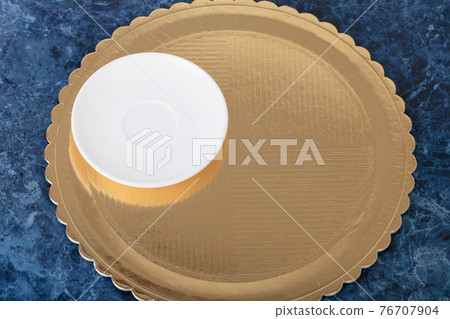Golden disposable cake tray and porcelain saucer. 76707904