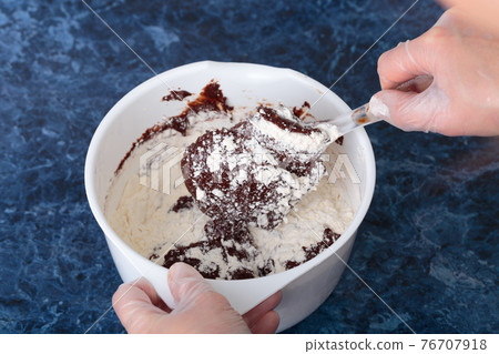 The process of mixing flour with chocolate mass. 76707918
