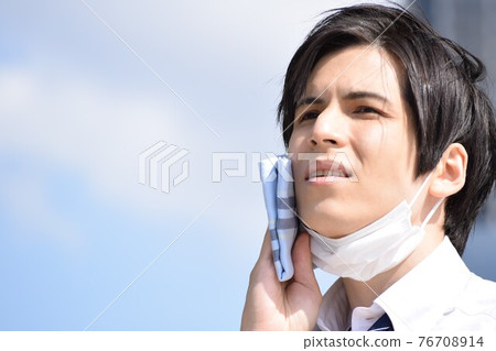 A young man who is hot and removes his mask and wipes his sweat with a handkerchief A young man who is hot and removes his mask and wipes his sweat with a handkerchief 76708914