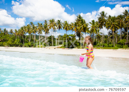Kids play on tropical beach. Sand and water toy. 76709597