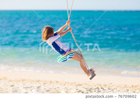 Child on swing. Kid swinging on beach. Child on swing. Kid swinging on beach. 76709602