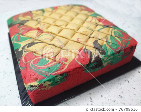 Sponge cake with colourful random patterns. Placed on a white table. Simple cake as a dessert. Sponge cake with colourful random patterns. Placed on a white table. Simple cake as a dessert. 76709616