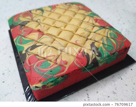 Sponge cake with colourful random patterns. Placed on a white table. Simple cake as a dessert. 76709617