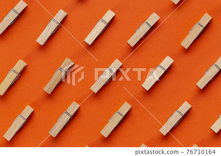 Many wooden clothespin on orange background. Many wooden clothespin on orange background. 76710164