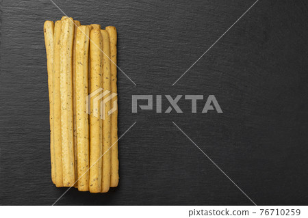 Homemade Italian Grissini Breadsticks on a black background.  76710259