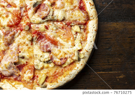 Fresh italian pizza with bacon, tomatoes, mushrooms and cheese on a wooden background.  76710275