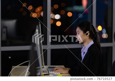 Asian young woman working overtime late at night in call center office. Asian young woman working overtime late at night in call center office. 76710527