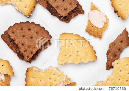 Pieces of chocolate chip cookies and biscuits with filling on a white plate close-up. 76710560