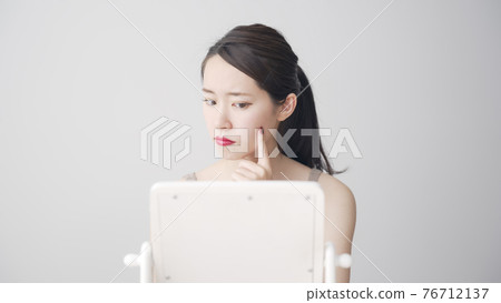 Woman looking at a mirror Beauty image Woman looking at a mirror Beauty image 76712137
