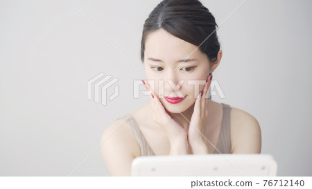 Woman looking at a mirror Beauty image Woman looking at a mirror Beauty image 76712140