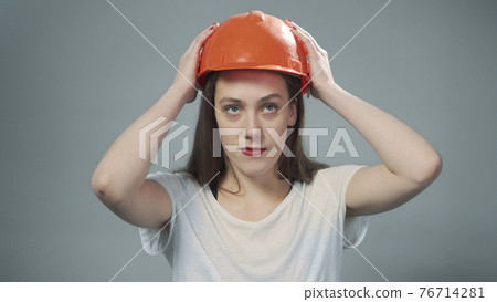 Photo of woman wearing orange helmet on grey Photo of woman wearing orange helmet on grey 76714281