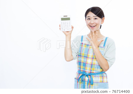 Housewife in her thirties doing calculations with a calculator Housewife in her thirties doing calculations with a calculator 76714400