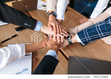 Top-View Of United Business Team Holding Hands In Office Top-View Of United Business Team Holding Hands In Office 76715405