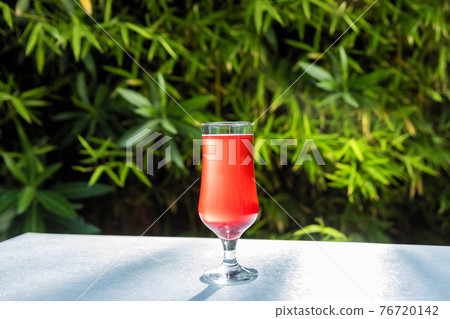 Red juice cocktail glass with green background Red juice cocktail glass with green background 76720142