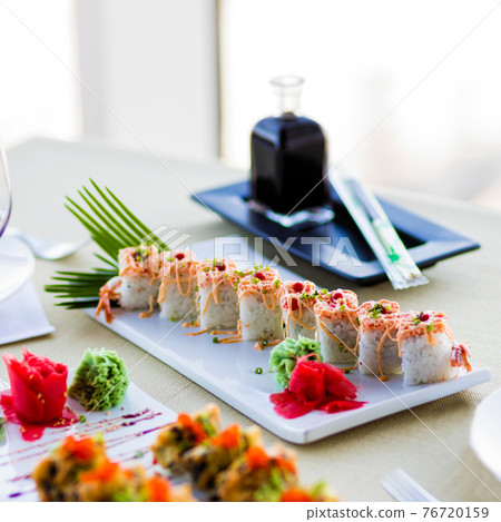 Sushi Set nigiri and sushi rolls with sauce served on white plate on the restaurant table 76720159