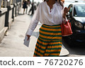 Detail of a fashionable outfit woman wearing white shirt, yellow and green skirt and red handbag 76720276
