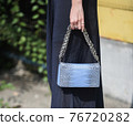 Detail of a fashionable outfit woman wearing blue dress and an aquamarine snake purse 76720282