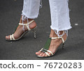 Detail of a fashionable outfit woman wearing white pants and white sandals with metal details 76720283