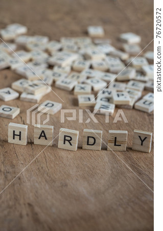the word hardly written with cube letters on wood background 76720572