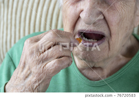 closeup of a senior person taking a vitamin capsule closeup of a senior person taking a vitamin capsule 76720583