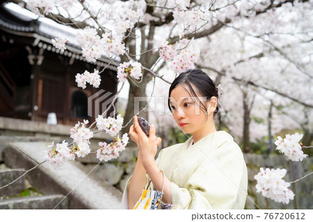 A woman in a kimono looking in the mirror 76720612
