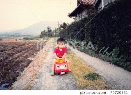 Old film photo: A boy riding a small car on a rural road 76720881