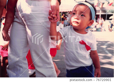 A boy holding a mother's hand at an old film photo athletic meet 76720901