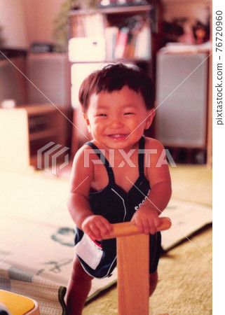 Old film photo: A smiling boy playing in a wooden car Old film photo: A smiling boy playing in a wooden car 76720960