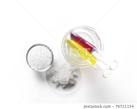 Microcrystalline wax in glass container, Flake salt in Chemical Watch Glass, Potassium Permanganate and Nickle chloride liquid in test tube. Cosmetic chemicals ingredient on laboratory table. Top view 76721154