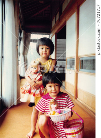 Old film photograph: Sisters of two girls playing dolls in the hallway of the house Old film photograph: Sisters of two girls playing dolls in the hallway of the house 76721717
