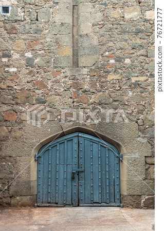 Ancient stone wall with a gate in the old castle. 76721777