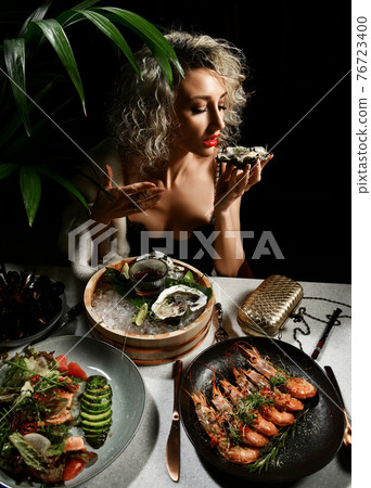 Blonde curly young woman in expensive evening 76723400