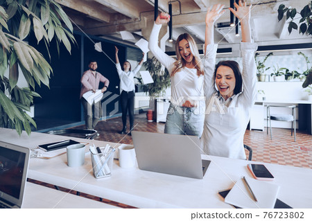 Two young happy businesswomen celebrating project success in office Two young happy businesswomen celebrating project success in office 76723802