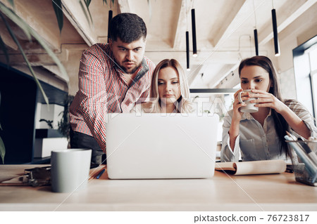 Two female and one male business partners looking at computer screen and discussing their project Two female and one male business partners looking at computer screen and discussing their project 76723817