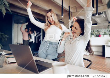 Two young happy businesswomen celebrating project success in office Two young happy businesswomen celebrating project success in office 76723872