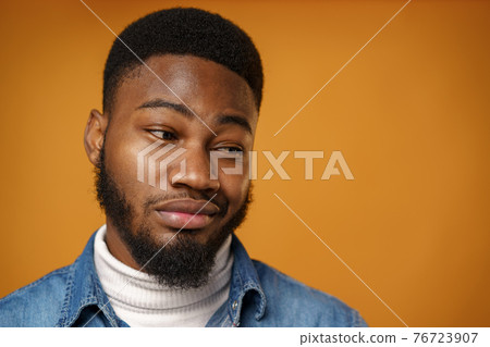 Young african american man frowns face being displeased against yellow background Young african american man frowns face being displeased against yellow background 76723907