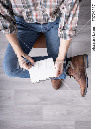 Men's hand holding pencil and notebook. Student male hand writing or drawing 76724387