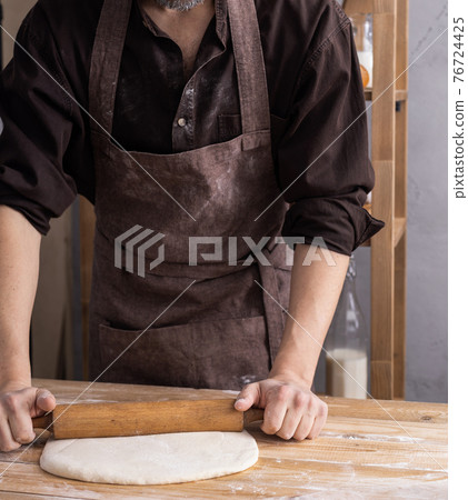 Baker man kneading or making dough or bread cooking. Bakery concept and wooden table 76724425