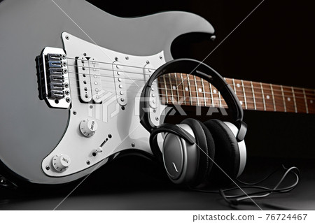 Electric guitar and headphones on black background Electric guitar and headphones on black background 76724467